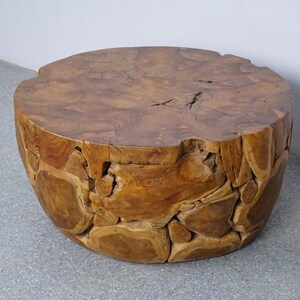 Op de afbeelding: Een ronde houten bijzettafel met een natuurlijke, onafgewerkte uitstraling. De tafel heeft een diameter van ongeveer 60 cm en is 45 cm hoog. Het hout heeft een warme, bruine kleur en een ruw, getextureerd oppervlak. De tafel is gemaakt van meerdere stukken hout.