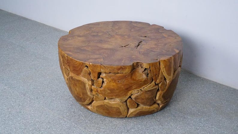 Op de afbeelding: Een ronde houten bijzettafel met een natuurlijke, onafgewerkte uitstraling. De tafel heeft een diameter van ongeveer 60 cm en is 45 cm hoog. Het hout heeft een warme, bruine kleur en een ruw, getextureerd oppervlak. De tafel is gemaakt van meerdere stukken hout.