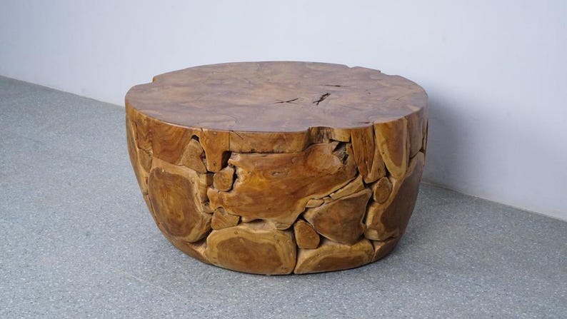 Op de afbeelding: Een ronde, handgemaakte houten salontafel. De tafel is gemaakt van natuurlijk hout, met een lichtbruin blad en een basis die is opgebouwd uit onregelmatig gevormde stukken hout. De tafel heeft een diameter van ongeveer 61 cm en is 46 cm hoog.