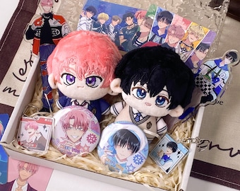 May include: A gift box containing two plush dolls with pink and black hair, two circular pin-back buttons, two acrylic character standees, and two square acrylic keychains featuring anime-style illustrations of characters with various expressions.