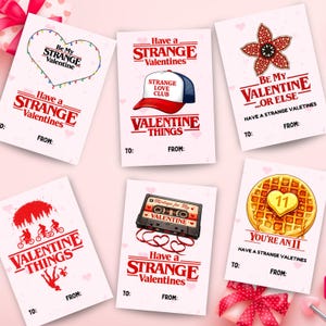 Puede incluir: Una colección de tarjetas de San Valentín con temática de 'Stranger Things'. Cada tarjeta presenta diseños y frases únicas como 'Be My Strange Valentine' y 'Have a Strange Valentine'. Las tarjetas tienen un fondo blanco con acentos rojos y rosas.
