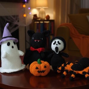 Pode incluir: Uma coleção de decorações de Halloween feitas à mão em crochê, incluindo um fantasma branco com chapéu roxo, um morcego preto com gravata borboleta vermelha, uma abóbora, uma figura de máscara Scream e uma aranha laranja e preta.