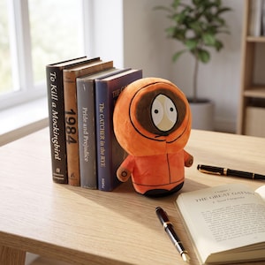 May include: A plush toy character wearing a bright orange hooded parka with a brown trim around the face, white oval eyes, and black pupils. The character is positioned next to a row of four hardcover books and an open book titled The Great Gatsby.