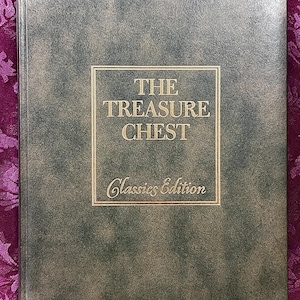 Può includere: Un libro con copertina rigida intitolato "The Treasure Chest Classics Edition". La copertina è verde screziato con una cornice rettangolare dorata contenente il titolo e i dettagli dell'edizione. Il libro è ambientato su uno sfondo viola a motivi.