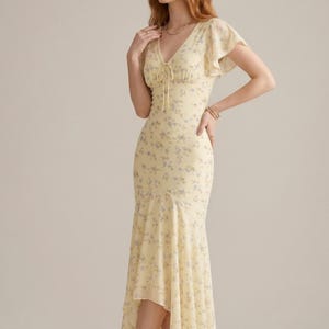 May include: A pale yellow midi dress featuring a delicate blue floral print, a V-neckline with a tie detail, flutter sleeves, and a high-low hemline. The dress is fitted through the bodice and flares out at the skirt, creating a flowing silhouette.