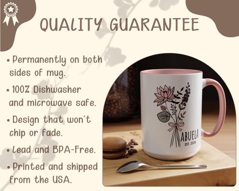 May include: White ceramic mug with a pink interior and handle. The mug features a floral bouquet design with the word "ABUELA" and "EST. 2000". The mug is on a wooden surface with a spoon and a macaron.