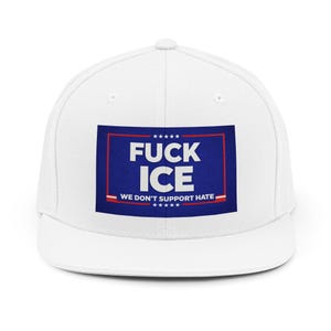 May include: White baseball cap with a flat brim. The front features a blue rectangle with the words "FUCK ICE" in white, and the text "WE DON'T SUPPORT HATE" below. The cap has a snapback closure.