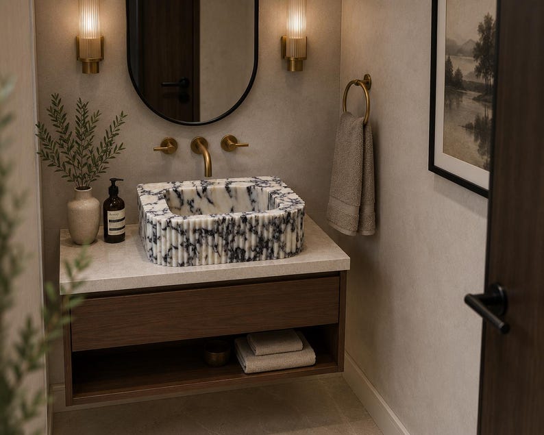 May include: A rectangular bathroom sink featuring a white and dark blue marbled pattern with a fluted exterior texture. The sink is mounted on a wooden vanity cabinet with a light stone countertop, brass faucet, and matching brass wall-mounted lighting.