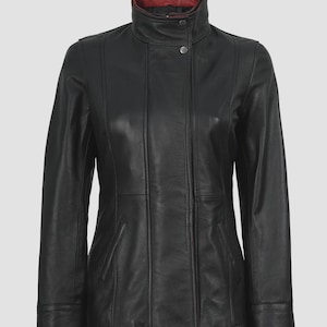 Könnte beinhalten: Schwarze Lederjacke mit hohem Kragen und rotem Innenfutter. Die Jacke hat einen Knopfverschluss am Kragen und vertikale Nähte auf der Vorderseite. Sie hat lange Ärmel und eine taillierte Passform.
