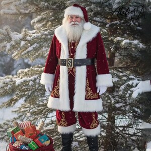 Op de afbeelding: Een kerstmanpak bestaande uit een donkerrode fluwelen jas en bijpassende broek met witte imitatiebontrand. De jas is voorzien van gouden borduursels, een zwarte riem met een gouden gesp in de vorm van een S en witte handschoenen.