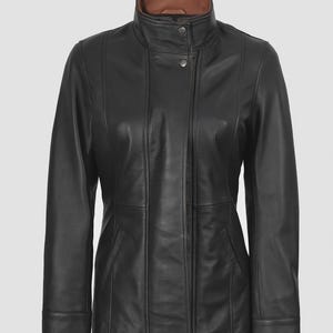 May include: A black leather jacket with a brown collar. The jacket has a stand-up collar, a button closure, and vertical seams. It features two front pockets and long sleeves. The jacket is a classic style.