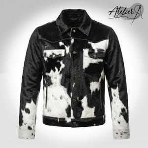 Puede incluir: Chaqueta de piel de vaca en blanco y negro con cuello clásico, dos bolsillos en el pecho y dos bolsillos laterales. La chaqueta tiene cierre de botones y cremallera a cada lado. Logotipo Atelier J.