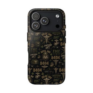 May include: A black smartphone case featuring a repeating pattern of military-themed graphics in gold and olive green. The design includes the text "DEVIL DOC," "CORPSMAN UP!," "FMF," "8404," and "GREENSIDE," alongside medical symbols and emblems.