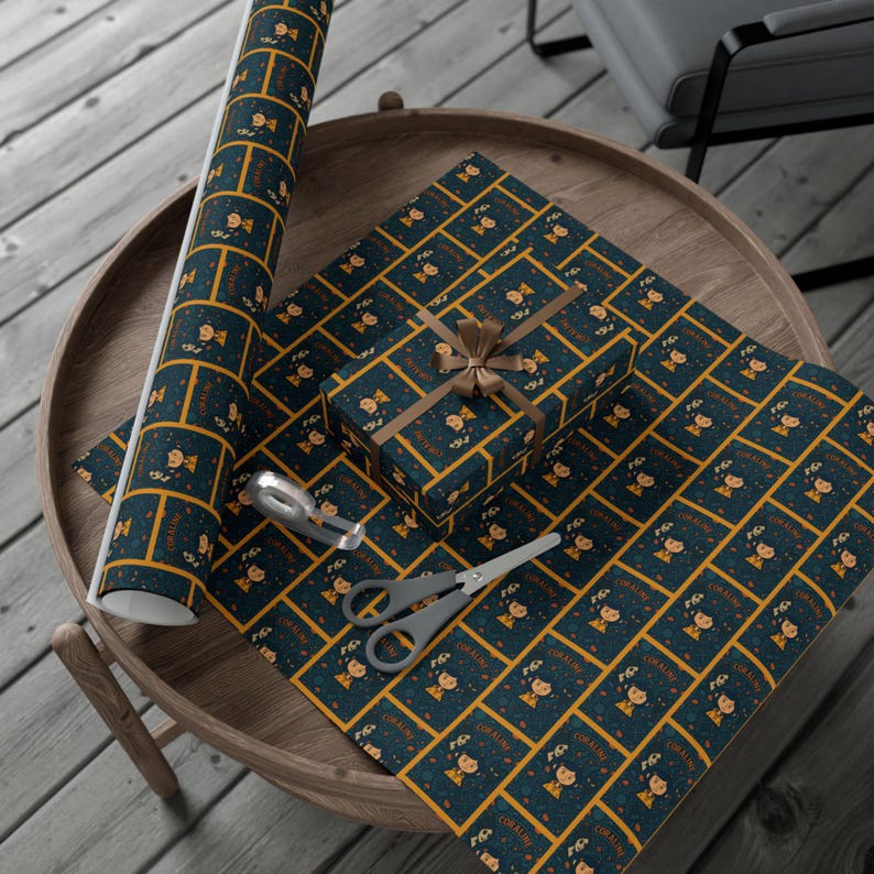 Op de afbeelding: Op een houten tafel liggen cadeaupapier, een ingepakt cadeau en een rol papier. Het donkerblauwe papier heeft een herhalend patroon van een stripfiguur en de naam "CORALINE" in goud. Een schaar en plakband zijn ook aanwezig.