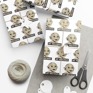 Pode incluir: Papel de embrulho branco com um personagem de desenho animado e os textos "My Precious" e "Precious". Os presentes são amarrados com barbante e uma etiqueta em forma de estrela. Também há um carretel de barbante e tesouras.