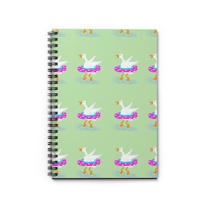 Könnte beinhalten: Spiralgebundenes Notizbuch mit einem sich wiederholenden Muster aus weißen Gänsen in rosa und blauen Schwimmringen auf hellgrünem Hintergrund. Die Gänse haben orangefarbene Schnäbel und Füße, was ein verspieltes und skurriles Design ergibt.