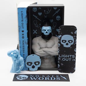 May include: A collection of horror-themed merchandise featuring a muscular figure with a skull mask, a Scream figure, and a bookmark. The items are in shades of blue and black, with the text "LIGHTS OUT" and "NO SAFE WORDS".
