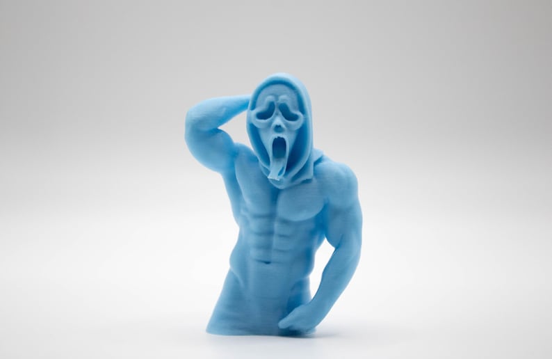 Puede incluir: Una escultura azul claro de una figura musculosa con una m&aacute;scara de Scream. La figura posa con un brazo levantado hacia la cabeza y la boca abierta en un grito. La escultura tiene abdominales definidos.