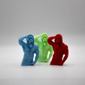 Puede incluir: Tres figuras coloridas del personaje de la m&aacute;scara de Scream. Las figuras son azules, verdes y rojas, cada una con un f&iacute;sico musculoso y una capucha. Las figuras posan con una mano en la cabeza.