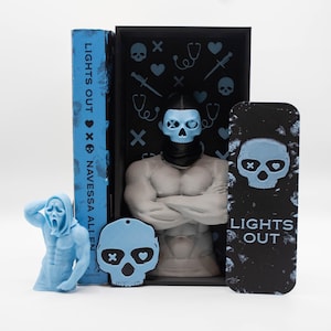 May include: A collection of horror-themed items, including a book titled "LIGHTS OUT" and a bookmark with the same title. The items feature a skull design and a figure with a skull mask. The color palette is primarily blue and black.