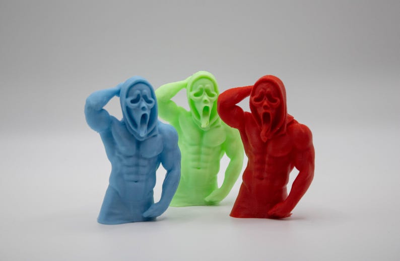 Puede incluir: Tres figuras coloridas del personaje de Ghostface de la serie de pel&iacute;culas de terror Scream. Las figuras son azules, verdes y rojas, cada una con una constituci&oacute;n muscular y la ic&oacute;nica m&aacute;scara. Las figuras posan con una mano en la cabeza.