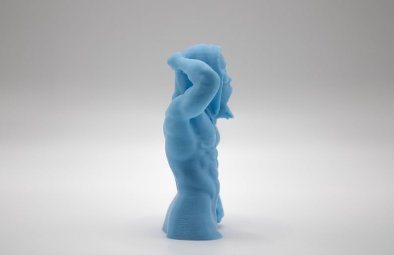 Puede incluir: Una escultura azul claro de una figura masculina musculosa, con un brazo levantado por encima de la cabeza. La figura tiene m&uacute;sculos abdominales definidos y est&aacute; de pie en una pose relajada. La escultura est&aacute; sobre un fondo blanco.