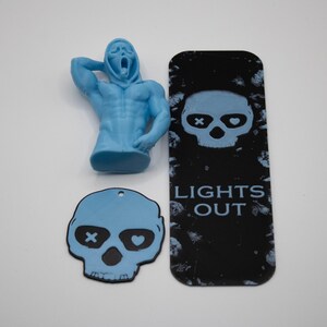 May include: A light blue Scream figure, a black bookmark with a skull design and the text "LIGHTS OUT", and a light blue skull-shaped tag with an X and a heart in the eyes. The items are on a white surface.