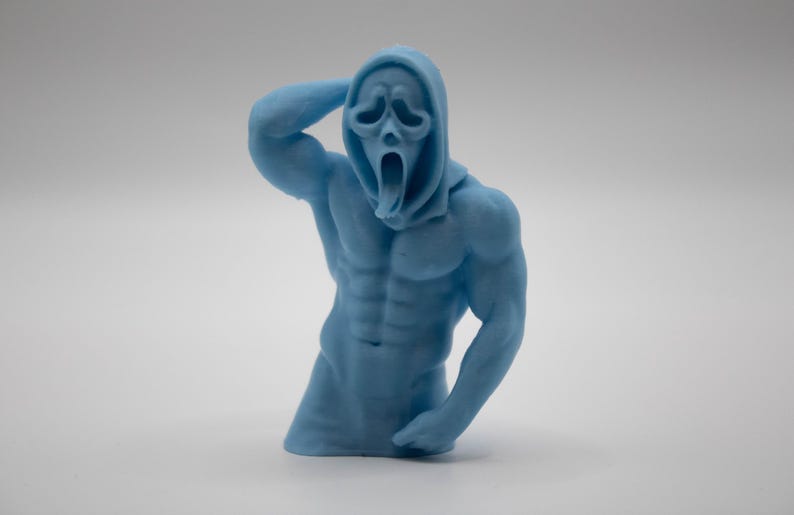 Puede incluir: Figura azul claro de una figura musculosa con una m&aacute;scara de Scream. La figura posa con un brazo levantado hacia la cabeza, mostrando abdominales definidos y brazos musculosos. Sobre un fondo blanco liso.