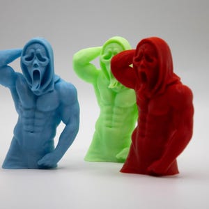 Puede incluir: Tres esculturas coloridas de una figura musculosa con una m&aacute;scara de Scream. Las figuras son azules, verdes y rojas. Las figuras tienen una capucha y est&aacute;n esculpidas con abdominales y brazos definidos.