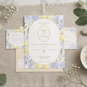 Könnte beinhalten: Hochzeitseinladungs-Set mit floralem Design in Gelb und Blau. Die Einladung zeigt die Namen "Abbie & Danny" und Veranstaltungsdetails. Enthält RSVP-Karten, einen Umschlag und Konfetti.