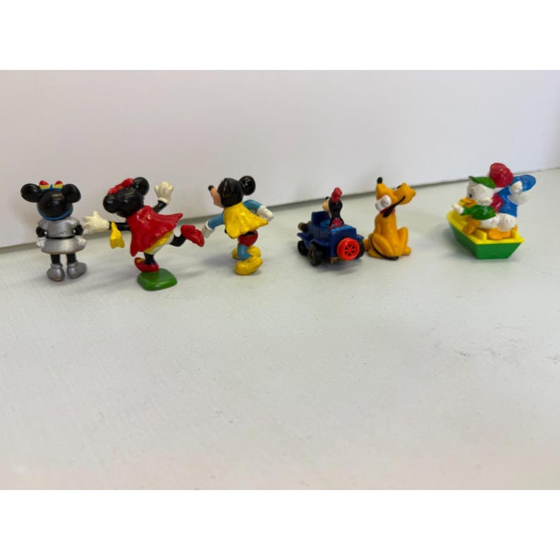 K&ouml;nnte beinhalten: Eine Sammlung kleiner, farbenfroher Disney-Charakterfiguren. Das Set enth&auml;lt Minnie Mouse, Mickey Mouse, Pluto, Donald Duck und einen Miniaturzug. Die Figuren sind aus Kunststoff und in verschiedenen Posen.