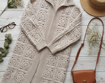 Puede incluir: Un cárdigan de crochet beige de manga larga y abierto por delante, con cuello. El cárdigan presenta un diseño de patrón cuadrado. También hay un bolso bandolera de cuero marrón, un sombrero de paja y gafas en la imagen.