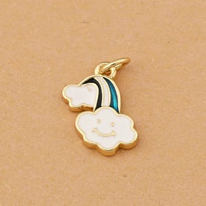 May include: A gold-coloured charm depicting a white cloud with a smiling face and a rainbow with black and teal stripes. The charm has a gold-coloured loop at the top for attaching to jewellery. The charm is likely made of metal and enamel.