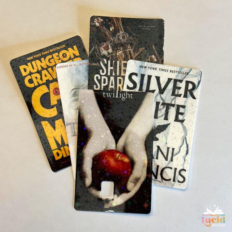 Op de afbeelding: Een verzameling rechthoekige stickers met boeken als thema. De stickers tonen boekomslagen met titels als "Dungeon Crave" en "Twilight". De stickers zijn zwart, wit en rood, met de tekst "New York Times Bestseller" op sommige.