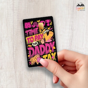 Puede incluir: Una tarjeta rectangular negra con ilustraciones gráficas vibrantes en rosa y amarillo que incluyen un gato, un hámster, un pie y un trofeo. El texto TIME TO PAY THE DADDY TAX aparece en letras negritas y estilizadas, junto a varios iconos pequeños.