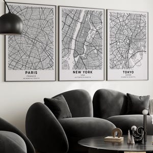 Peut inclure: Trois affiches murales encadrées représentant des plans de ville en noir et blanc de Paris, New York et Tokyo. Chaque impression affiche le nom de la ville, le pays et les coordonnées géographiques en noir sur fond blanc, sous des cadres noirs.