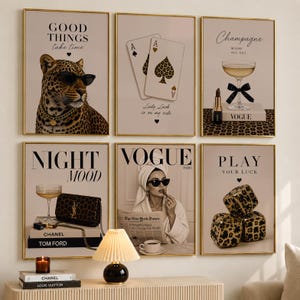 May include: A set of six framed wall art prints featuring a leopard wearing sunglasses, playing cards, a champagne glass with a lipstick, a handbag on books, a person reading a newspaper, and leopard print dice, all with text and gold frames.
