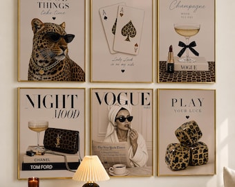 May include: A set of six framed wall art prints featuring a leopard wearing sunglasses, playing cards, a champagne glass with a lipstick, a handbag on books, a person reading a newspaper, and leopard print dice, all with text and gold frames.