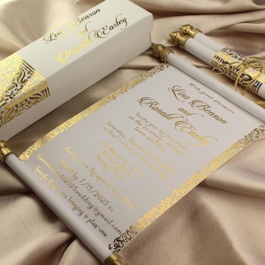 May include: Elegant wedding invitation scroll with gold foil accents. The invitation features the names "Lisa Benson and Ronald Easley" in a decorative font. Includes a matching box and scroll holders with gold tassels.