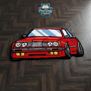 May include: A red car-shaped rug with black wheels and a blue windshield. The rug has yellow headlights and the text "Pro Rug Original" in a blue circle.