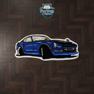 May include: A blue car-shaped rug with black tires and a white border. The rug features a stylized design of a classic car. The logo "Pro Rug Original" is visible in the upper right corner.