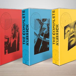 May include: Three rectangular media cases labelled The Complete Kubrick, numbered 1, 2, and 3. The first case is red with a black portrait, the second is blue with a black space station graphic, and the third is yellow with a black stippled face graphic.