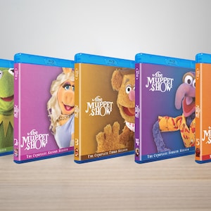 May include: A collection of five Blu-ray disc sets of "The Muppet Show" seasons 1-5. Each case features a different Muppet character on the cover, including Kermit, Miss Piggy, Fozzie Bear, Gonzo, and Animal. The cases have a blue border.