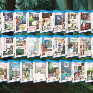 May include: A collection of Blu-ray movie cases featuring various animated films. The cases have blue borders and white spines with Japanese text and colorful illustrations. Titles include "My Neighbor Totoro," "Spirited Away," and "Princess Kaguya."