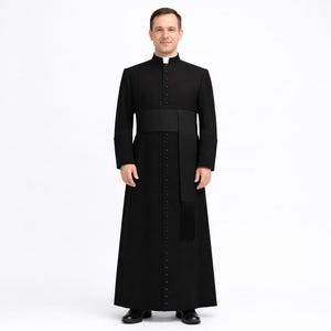 Könnte beinhalten: Eine schwarze Priesterkutte mit weißem Kragen, Knopfleiste und schwarzem Schärpe. Das lange, fließende Kleidungsstück wird mit schwarzen Schuhen getragen. Die Soutane ist ein traditionelles Kleidungsstück, das von Geistlichen getragen wird.