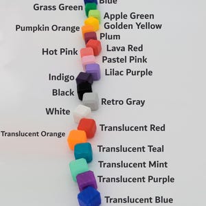 Pu&ograve; includere: Una tabella colori con piccoli oggetti quadrati in varie tonalit&agrave;. I colori includono blu, verde, arancione, rosa e viola, con etichette come "Verde Erba" e "Blu Traslucido".