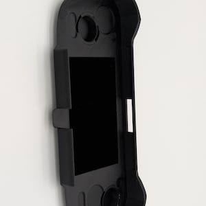 Pu&ograve; includere: Una custodia protettiva nera per un dispositivo di gioco portatile. La custodia ha un'apertura rettangolare per lo schermo e pulsanti sagomati. Realizzata in materiale nero opaco, &egrave; progettata per proteggere il dispositivo.