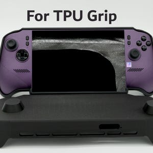 May include: A purple handheld gaming console with black joysticks and buttons, featuring a black screen. The text For TPU Grip is displayed above the device, which is positioned behind a black, textured, rectangular plastic grip accessory.