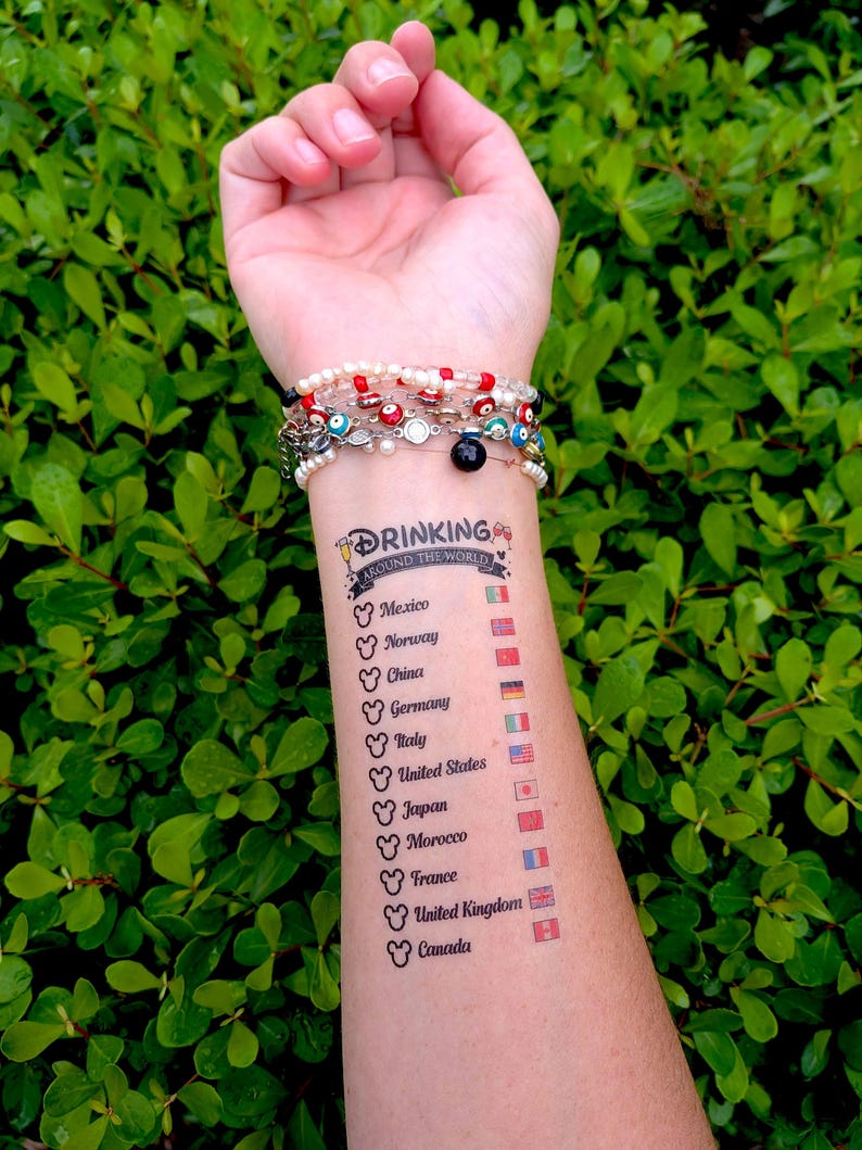 Op de afbeelding: Een tijdelijke tatoeage op een arm met de tekst Drinking Around The World, Mickey Mouse-oorpictogrammen en een lijst met landen waaronder Mexico, Noorwegen, China, Duitsland, Itali&euml;, Verenigde Staten, Japan, Marokko, Frankrijk, Verenigd Koninkrijk en Canada.