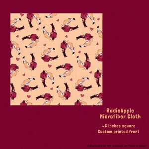 May include: A square microfiber cloth with a repeating pattern of cartoon characters in shades of red, black, and tan, with small pink hearts on a light peach background. The cloth is approximately 6 inches square.